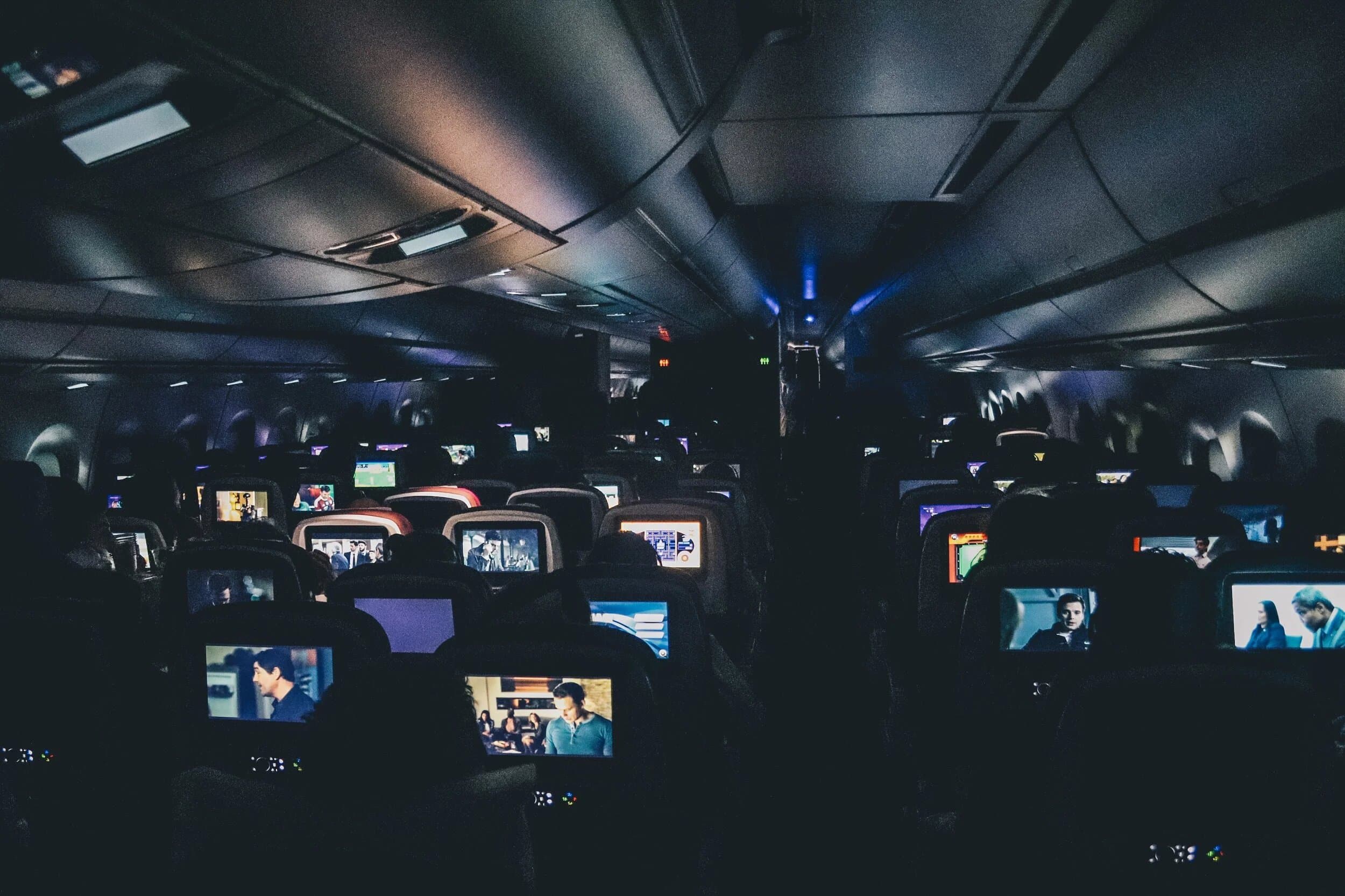 Seat-back entertainment screens glowing in a darkened aircraft cabin
