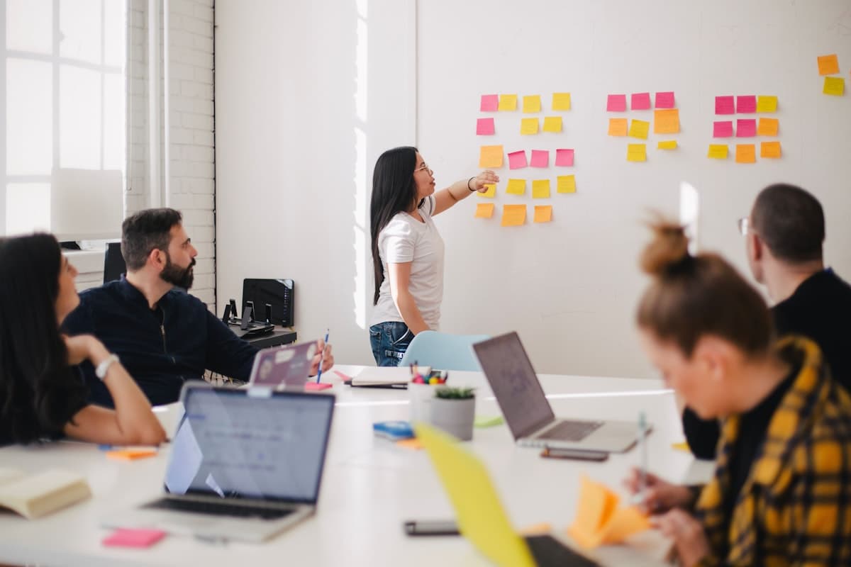 A team workshop with sticky notes mapped on a wall and laptops open on the table