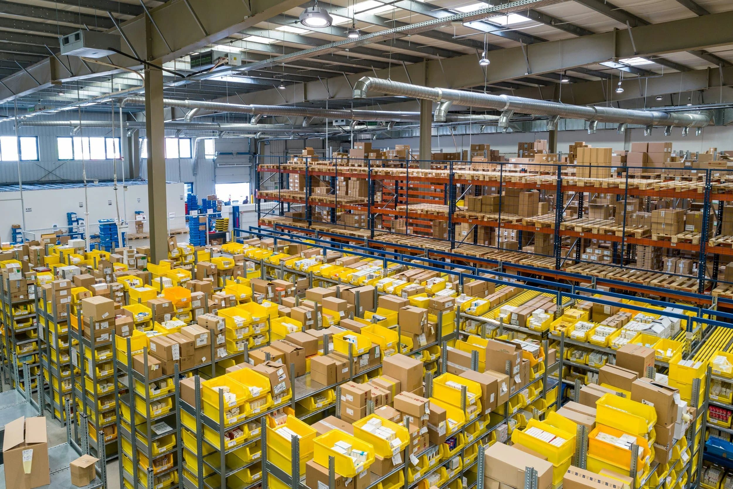 Warehouse racking stocked with boxes and yellow picking totes