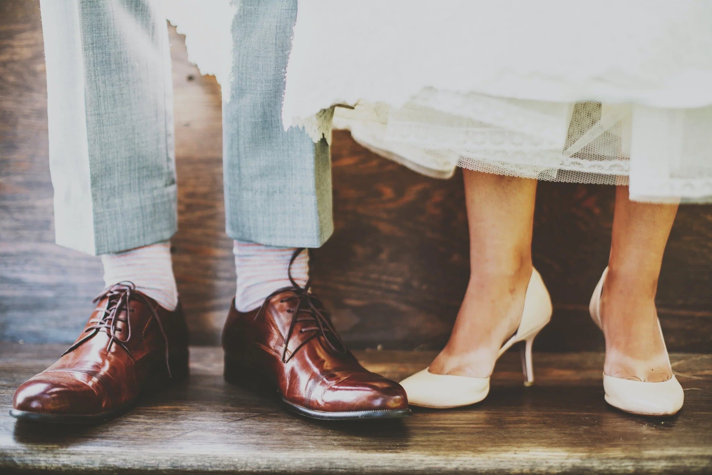 Two pairs of formal shoes side by side on a wooden step