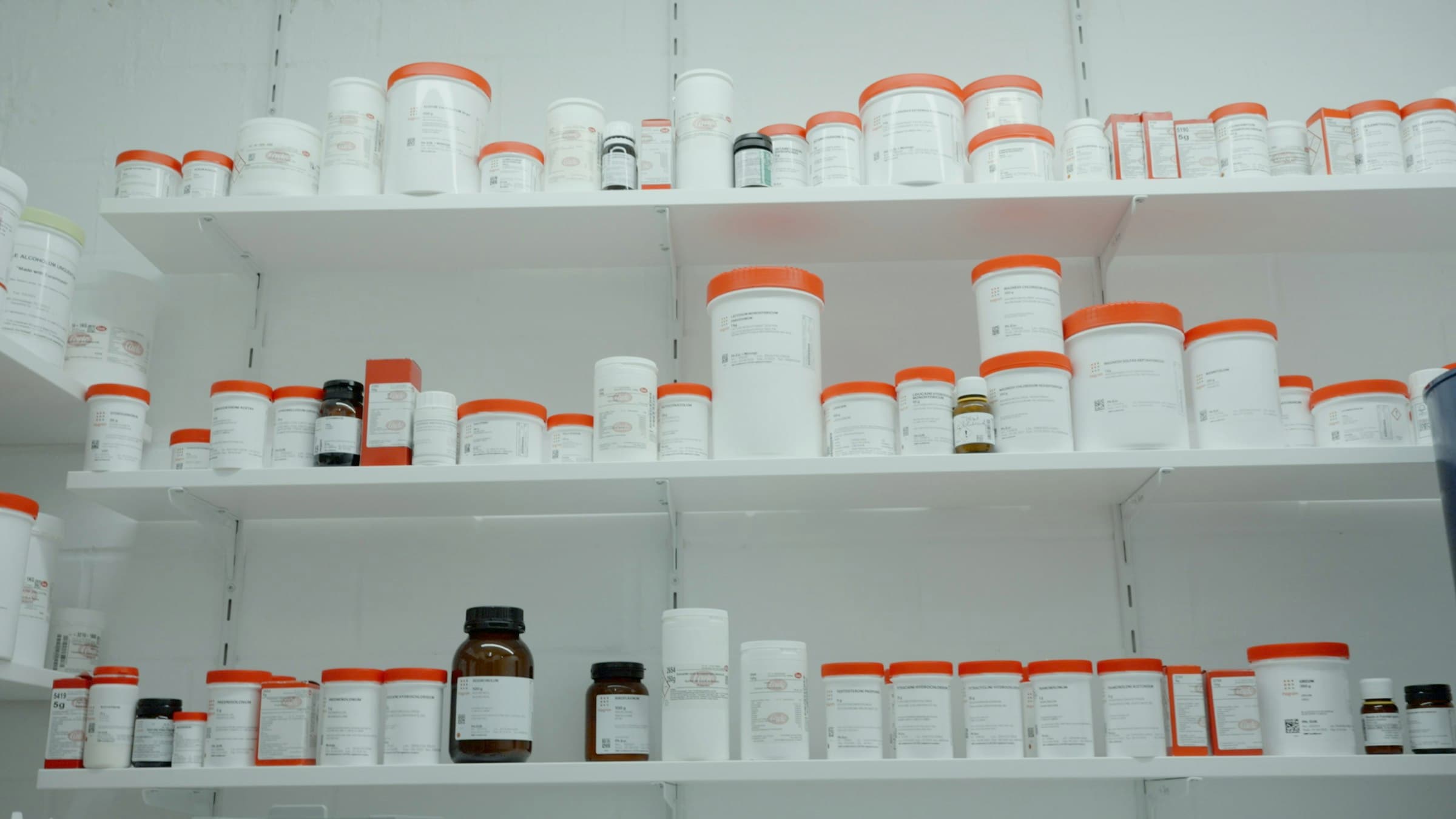 White pharmacy shelving stocked with medicine containers.
